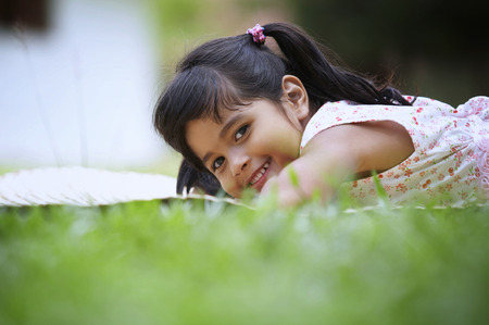 close up of girl lying on the grass looking at the cameraの写真素材