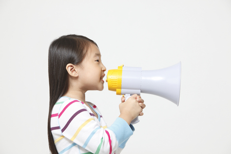 Side view of little girl holding loud speakerの写真素材