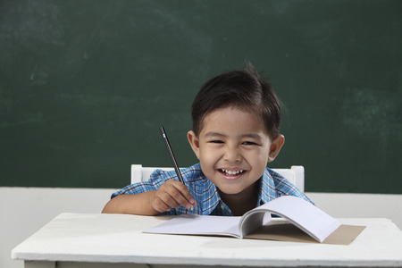 malay boy sitting in the classroom holding pencilの写真素材