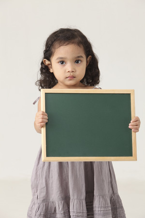 Portrait of girl holding blank blackboardの写真素材