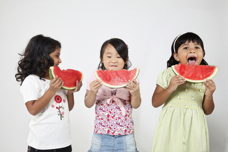 Three kids eating watermelonの写真素材