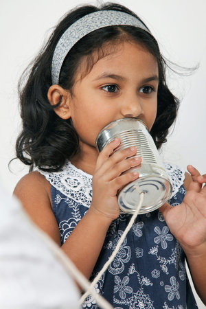 close up on Indian girl holding tin can phoneの写真素材