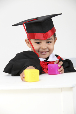 stock image of the boy wearing graduation gown playing colorful blockの写真素材