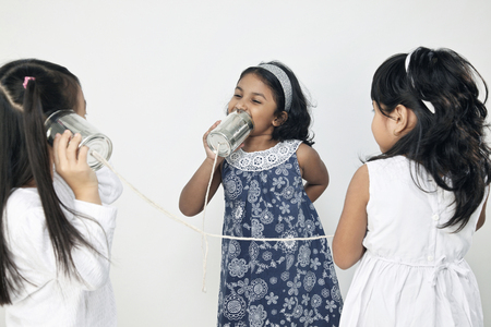 Three girls playing with tin can phonesの写真素材