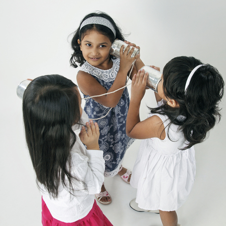 Three girls playing tin can telephonesの写真素材