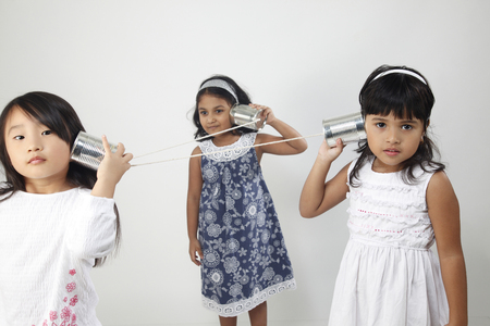 Three girls playing tin can telephonesの写真素材