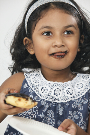 little Indian girl eating doughnutの写真素材