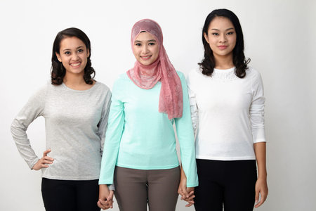 three multi racial malaysian holding hand looking at cameraの写真素材