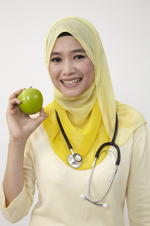 malay female doctor holding green appleの写真素材