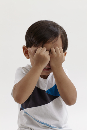 Portrait of young malay boy on white backdrop, cryingの写真素材