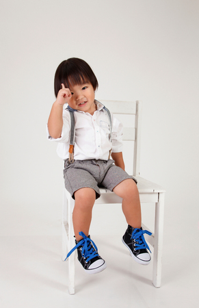 chinese boy sitting on the big stool raising his handの写真素材