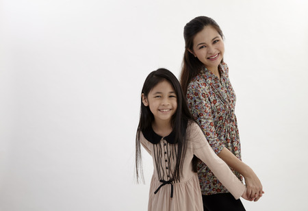 malay happy mother and daughter holding hand and standing back to backの写真素材