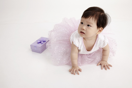 chinese baby wearing party dress with purple gift boxの写真素材