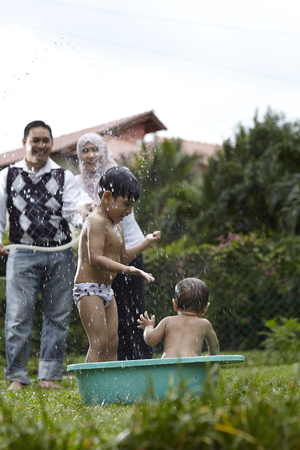 parent splashing water to their childrenの写真素材
