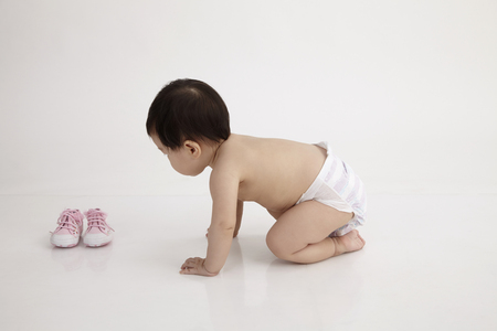 chinese baby girl picking up a shoeの写真素材