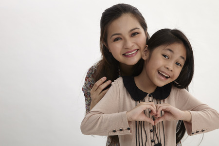 Portrait of happy mother and young daughter with heart shape sign - isolated on white backgroundの写真素材