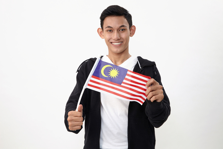 malay teenage holding a small malaysiasia flagの写真素材