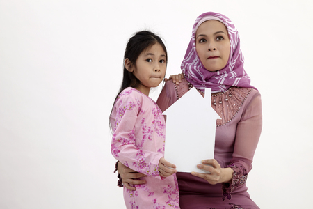 malay mother and daughter holding house shape card board with worried expressionの写真素材