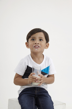 malay boy holding a glass of milkの写真素材