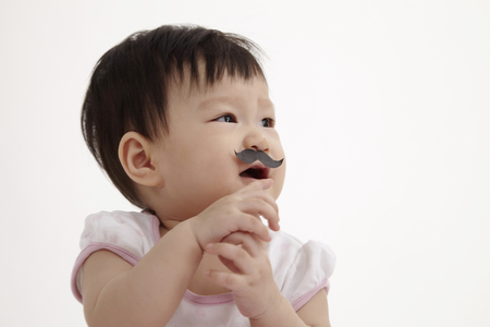 chinese baby girl look funny with paper moustacheの写真素材