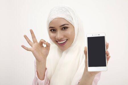 portrait of malay woman holding phone with ok signの写真素材