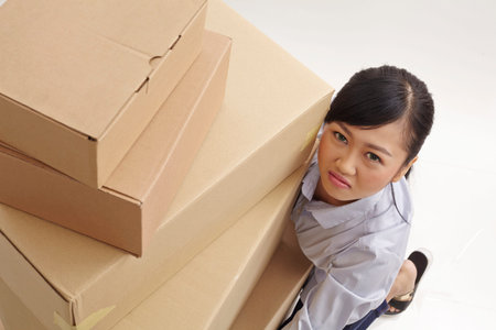 high angle view of asian woman lifting stack of boxes