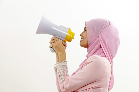 malay woman speaking into a megaphone making a public announcement isolated on whiteの写真素材