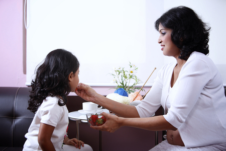 Pregnant woman feeding little girl strawberriesの写真素材