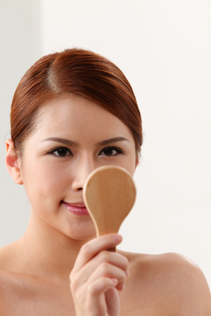 Young woman holding mirror on the white backgroundの写真素材