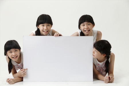 few girl with same look pointing at blank cardboardの写真素材
