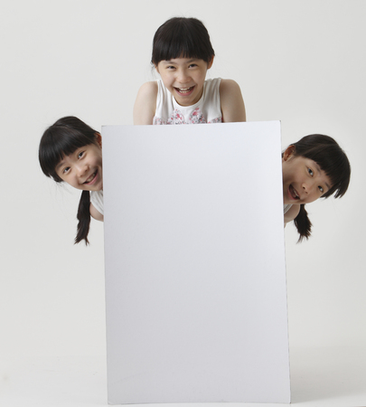 few girl with same look hiding blank cardboardの写真素材