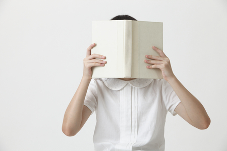 chinese girl holding a blank cover book covering her faceの写真素材