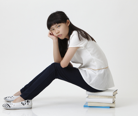 chinese girl sat on  books looking at cameraの写真素材
