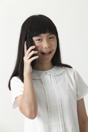 chinese girl talking with cellphone looking at cameraの写真素材