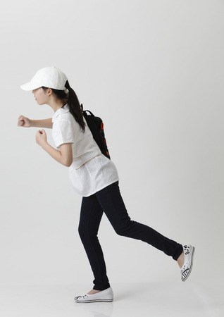 girl with backpack and cap in the running positionの写真素材