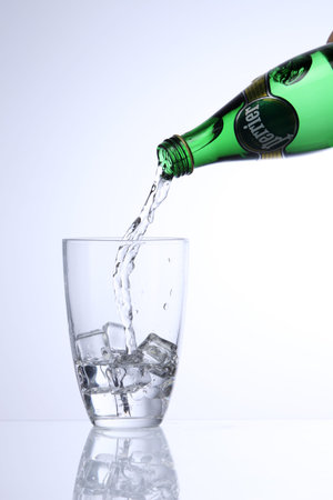 KUALA LUMPUR, MALAYSIA - Feb 17, 2016 pouring perrier mineral water into glass with ice cubeのeditorial素材