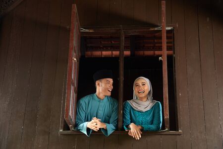 malay young couple at the wooden window of a traditional malay houseの写真素材