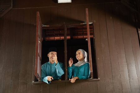 malay young couple at the wooden window of a traditional malay houseの写真素材