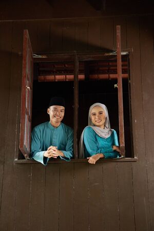 malay young couple at the wooden window of a traditional malay houseの写真素材