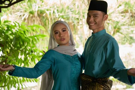front view of malay couple standing in front of house waiting for visitorsの写真素材