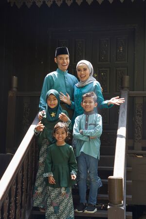 malay family standing at front yard wavingwith welcome gestureの写真素材