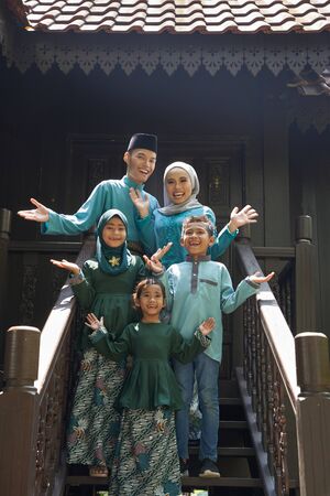 malay family standing at front yard wavingwith welcome gestureの写真素材
