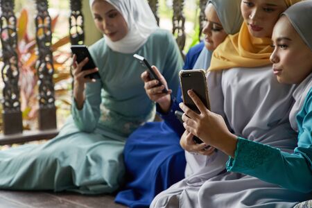 women with traditional clothing using smart phone during ramadan festival celebrationの写真素材