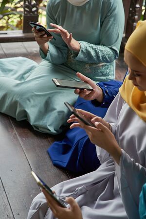 women with traditional clothing using smart phone during ramadan festival celebrationの写真素材