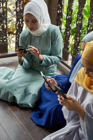 women with traditional clothing using smart phone during ramadan festival celebrationの写真素材