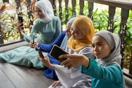 women with traditional clothing using smart phone during ramadan festival celebrationの写真素材