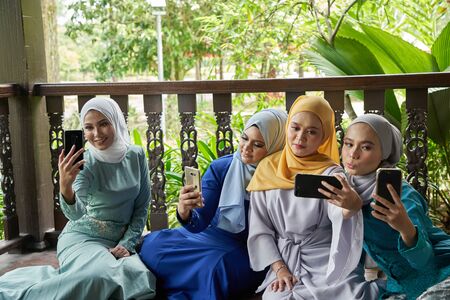 women with traditional clothing using smart phone during ramadan festival celebrationの写真素材