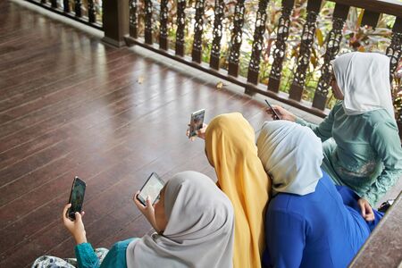 women with traditional clothing using smart phone during ramadan festival celebrationの写真素材