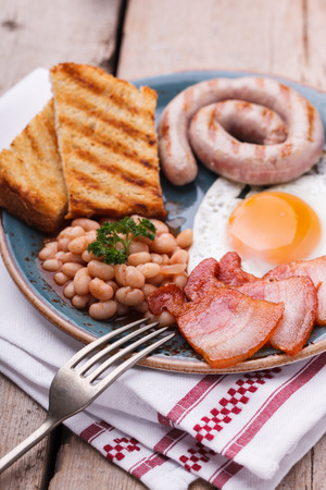 English breakfast with fried eggs, bacon, sausages, beans, toasts. selective focus.の写真素材