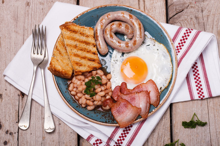 English breakfast with fried eggs, bacon, sausages, beans, toasts. selective focus.の写真素材